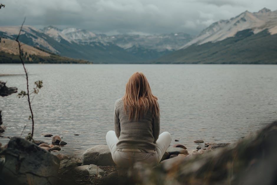 person sitting peacefully by a calm lake - wellness retreats for depression person sitting peacefully by a calm lake - wellness retreats for depression